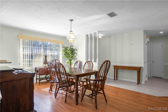 dining space with a textured ceiling and light hardwood / wood-style flooring