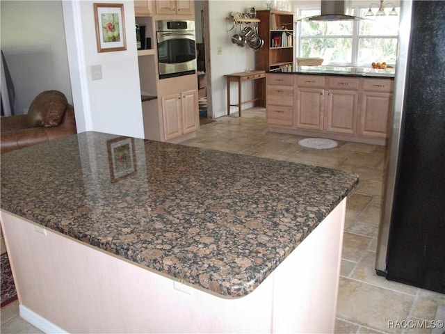 kitchen with stainless steel appliances, exhaust hood, dark stone counters, light brown cabinets, and a chandelier