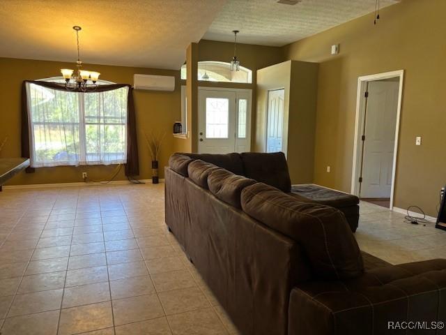 living area featuring baseboards, a wall unit AC, a notable chandelier, and plenty of natural light