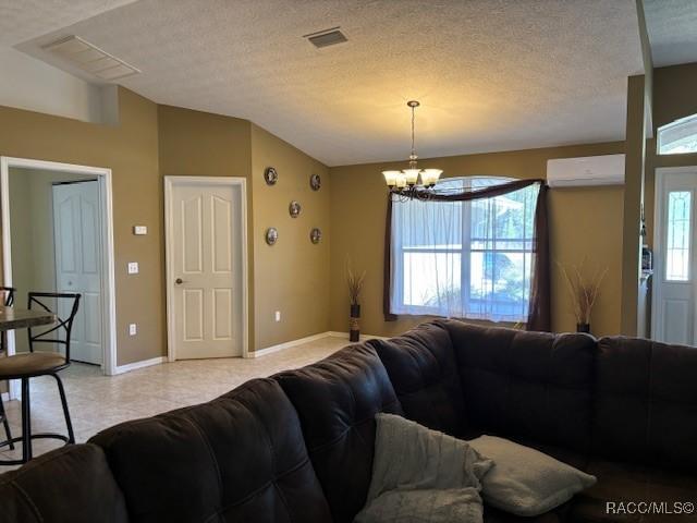 living area featuring a chandelier, a wealth of natural light, a wall mounted air conditioner, and lofted ceiling