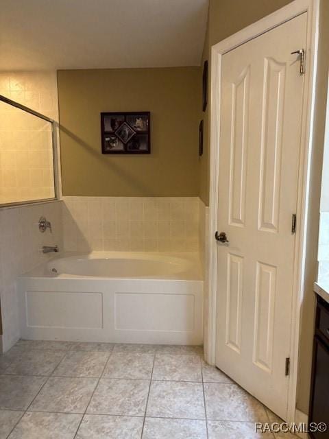 bathroom with tile patterned floors, vanity, and a garden tub