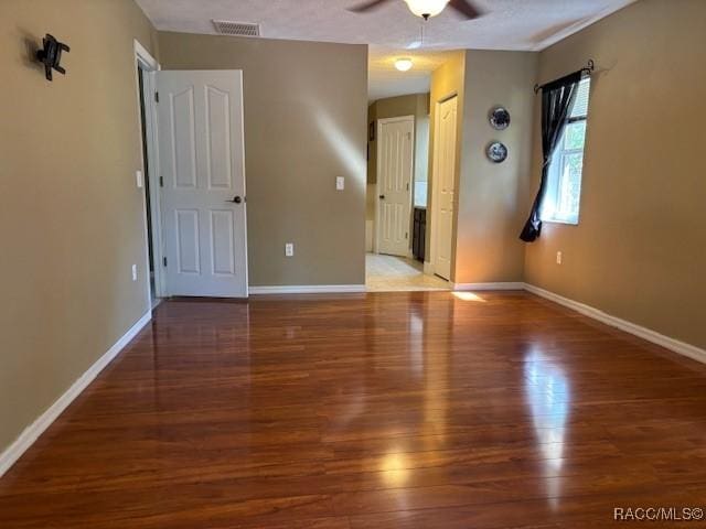 unfurnished bedroom with ceiling fan, visible vents, baseboards, and wood finished floors