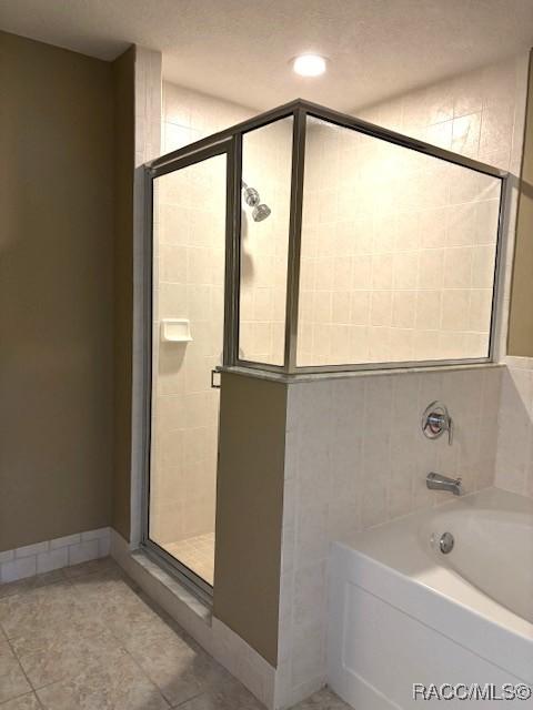 full bath with baseboards, a shower stall, tile patterned flooring, and a garden tub