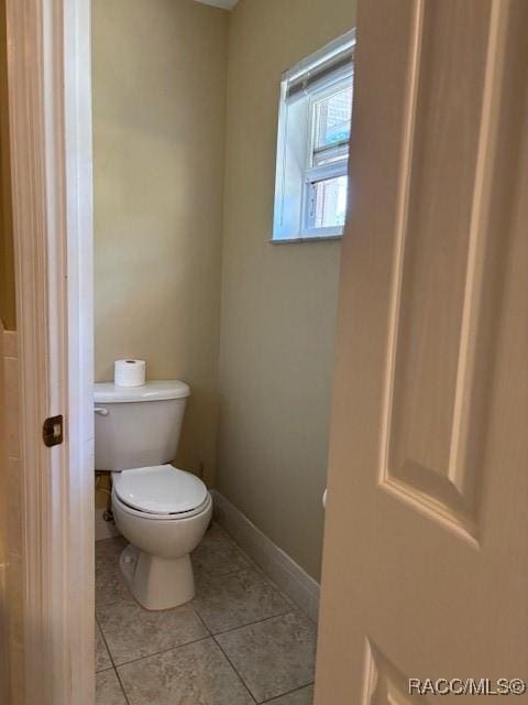 bathroom featuring toilet, baseboards, and tile patterned flooring