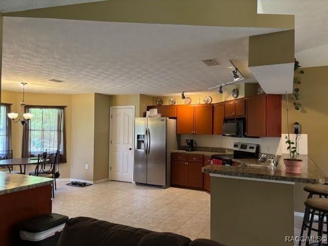 kitchen featuring a peninsula, visible vents, stainless steel appliances, a breakfast bar area, and baseboards