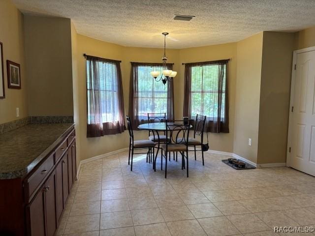 dining area featuring a textured ceiling, visible vents, an inviting chandelier, and light tile patterned floors