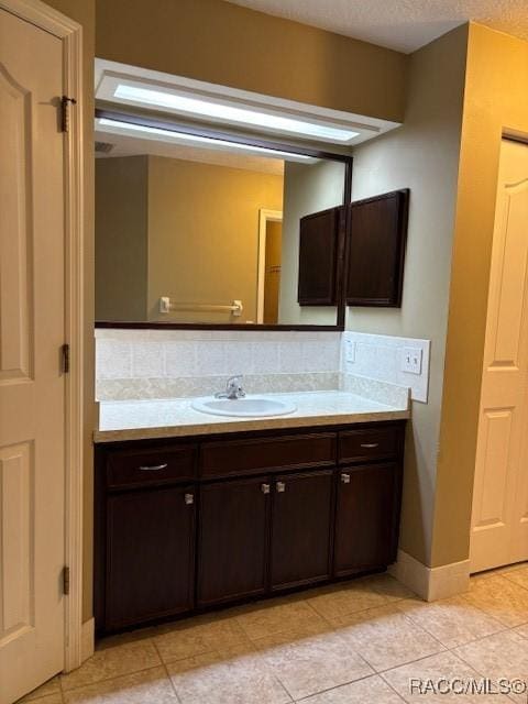 bathroom featuring backsplash, vanity, baseboards, and tile patterned flooring