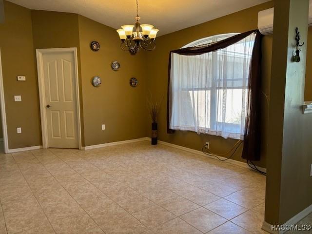 spare room with baseboards, an inviting chandelier, light tile patterned flooring, and a wall mounted air conditioner