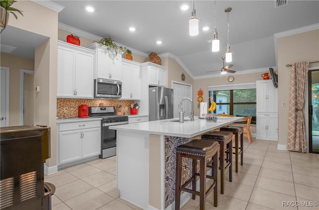 kitchen with a breakfast bar area, hanging light fixtures, stainless steel appliances, a kitchen island with sink, and white cabinets