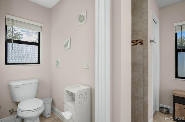 bathroom featuring tile patterned floors, toilet, and a tile shower