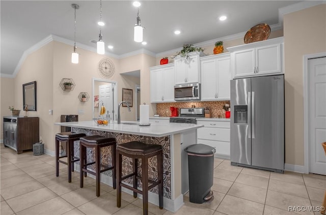 kitchen featuring an island with sink, appliances with stainless steel finishes, pendant lighting, and white cabinets