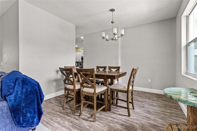 dining space featuring hardwood / wood-style flooring, a notable chandelier, a textured ceiling, and a wealth of natural light