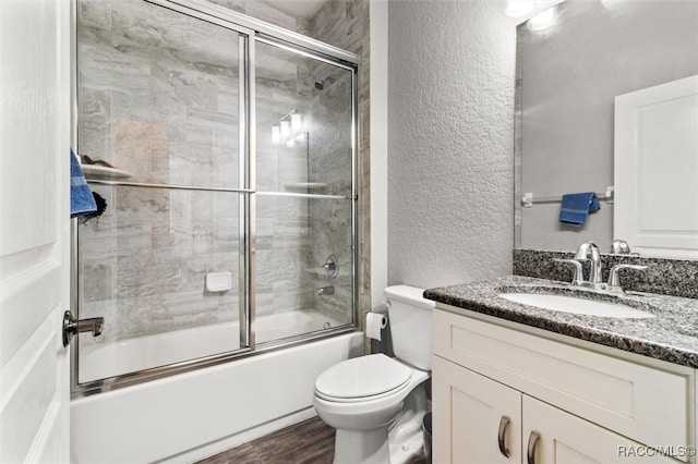 full bathroom with hardwood / wood-style floors, vanity, bath / shower combo with glass door, and toilet