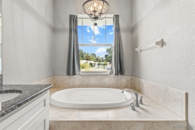 bathroom featuring tiled bath, vanity, and an inviting chandelier