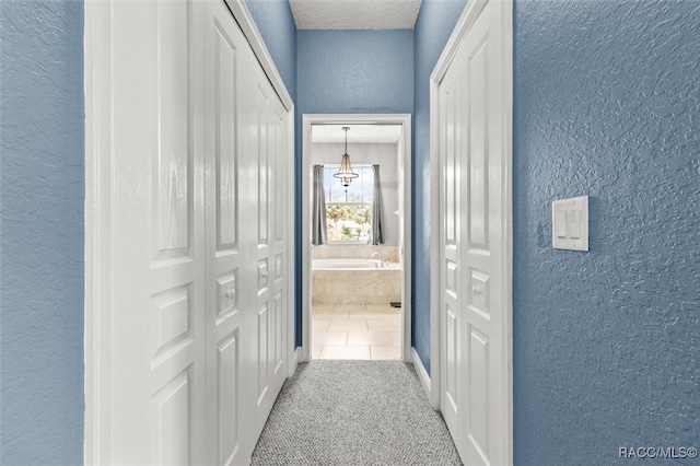 corridor featuring light colored carpet and a textured ceiling