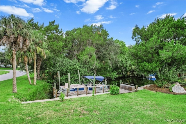 view of home's community with a lawn, a water view, and a dock