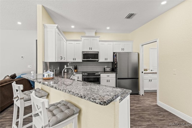 kitchen with white cabinets, a textured ceiling, appliances with stainless steel finishes, and tasteful backsplash