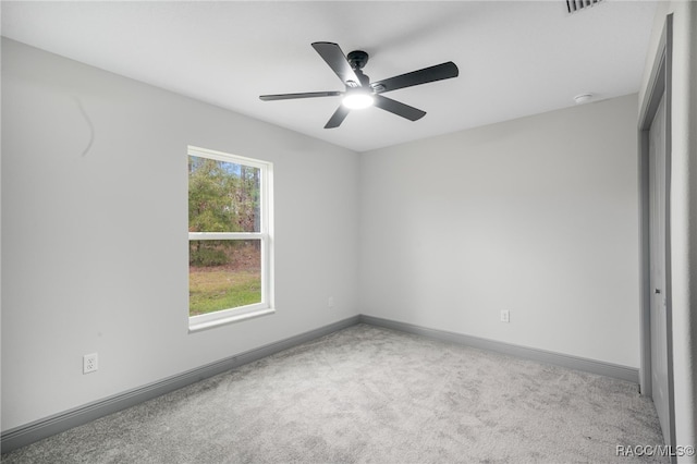 carpeted spare room featuring ceiling fan and a wealth of natural light