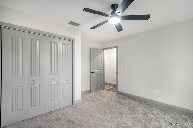 unfurnished bedroom featuring ceiling fan, light colored carpet, and a closet