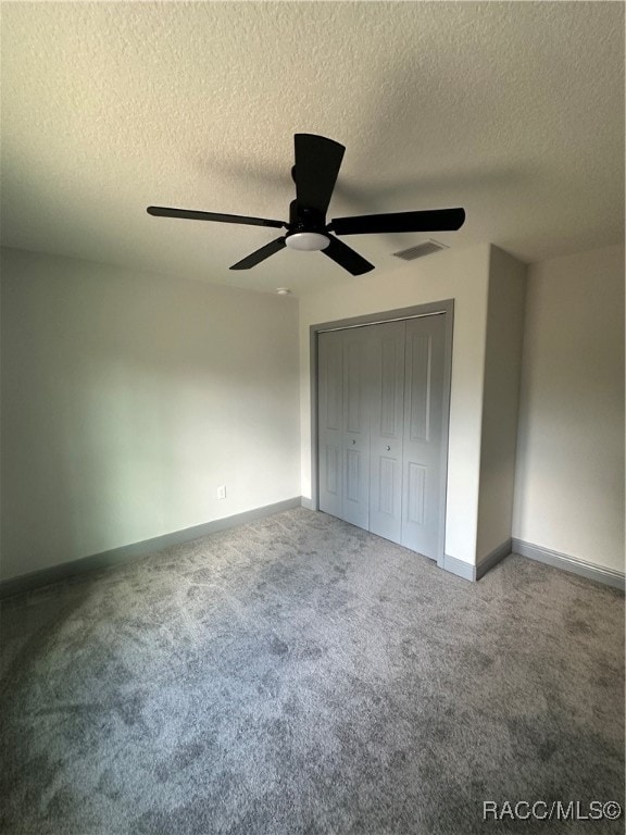 unfurnished bedroom featuring ceiling fan, a textured ceiling, a closet, and carpet flooring