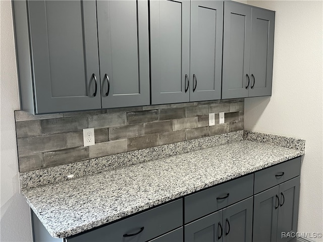 kitchen with light stone countertops, decorative backsplash, and gray cabinets