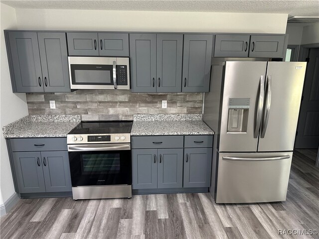 kitchen with dark wood-type flooring, appliances with stainless steel finishes, and gray cabinetry