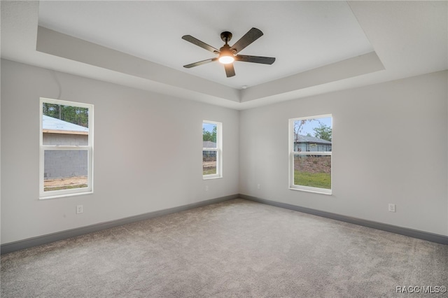 unfurnished room with ceiling fan, a raised ceiling, and carpet flooring