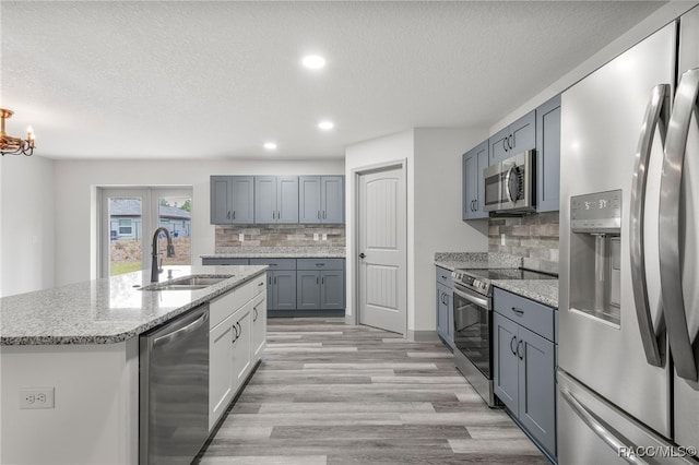 kitchen featuring an inviting chandelier, a center island with sink, appliances with stainless steel finishes, backsplash, and sink