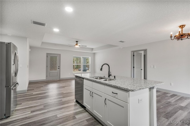 kitchen with ceiling fan with notable chandelier, appliances with stainless steel finishes, white cabinetry, sink, and a raised ceiling