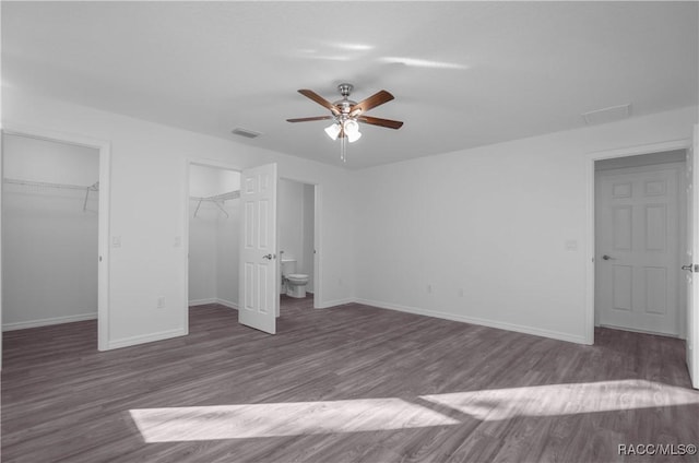 unfurnished bedroom with dark hardwood / wood-style flooring, connected bathroom, a spacious closet, and ceiling fan