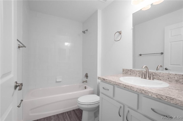 full bathroom with tiled shower / bath combo, wood-type flooring, vanity, and toilet