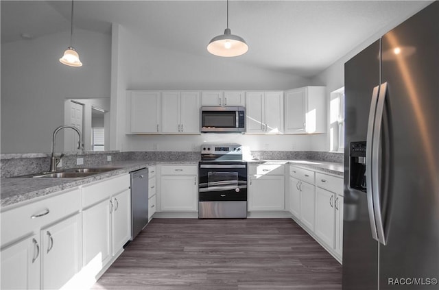 kitchen with appliances with stainless steel finishes, vaulted ceiling, hanging light fixtures, and white cabinets