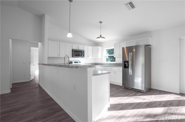 kitchen featuring white cabinetry, decorative light fixtures, vaulted ceiling, appliances with stainless steel finishes, and dark hardwood / wood-style floors