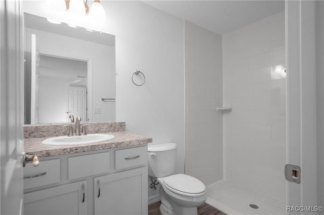 bathroom with vanity, toilet, and a tile shower