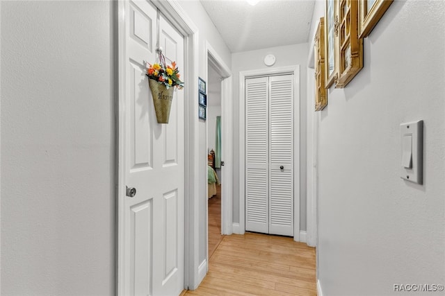 hall featuring light hardwood / wood-style flooring and a textured ceiling