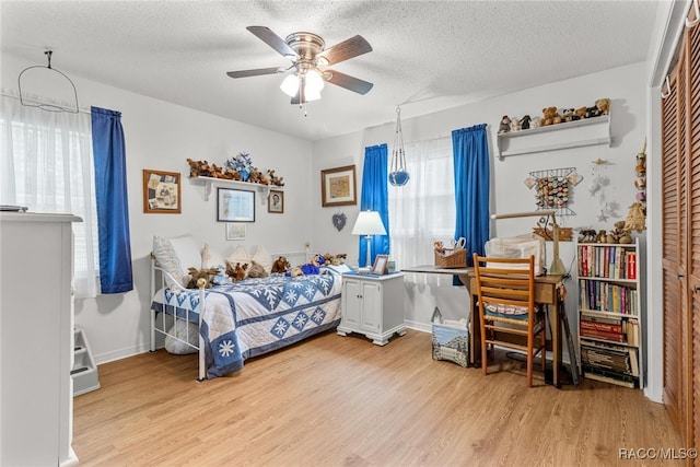 bedroom featuring ceiling fan, a closet, a textured ceiling, and light wood-type flooring