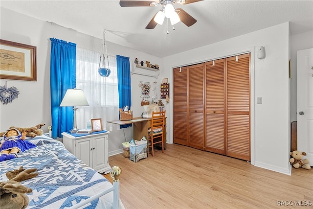 bedroom featuring a textured ceiling, light wood-type flooring, a closet, and ceiling fan