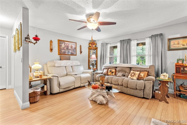 living room with a textured ceiling, light hardwood / wood-style flooring, and ceiling fan