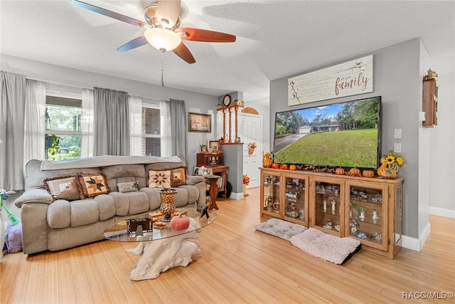 living room featuring hardwood / wood-style flooring, ceiling fan, and a textured ceiling