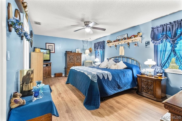 bedroom with multiple windows, ceiling fan, a textured ceiling, and light wood-type flooring