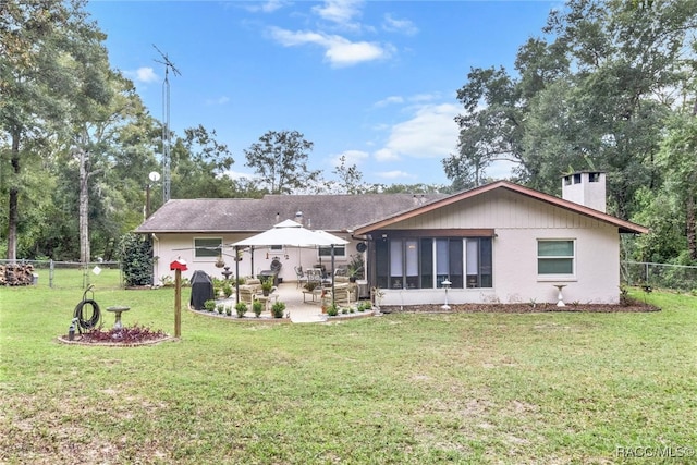 rear view of house with a sunroom, a patio area, and a lawn