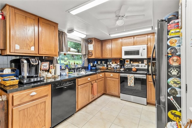 kitchen featuring appliances with stainless steel finishes, a raised ceiling, ceiling fan, sink, and light tile patterned flooring