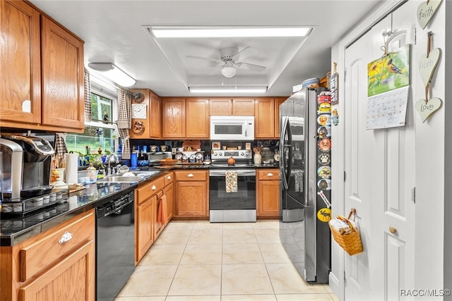 kitchen with appliances with stainless steel finishes, a tray ceiling, ceiling fan, sink, and light tile patterned flooring