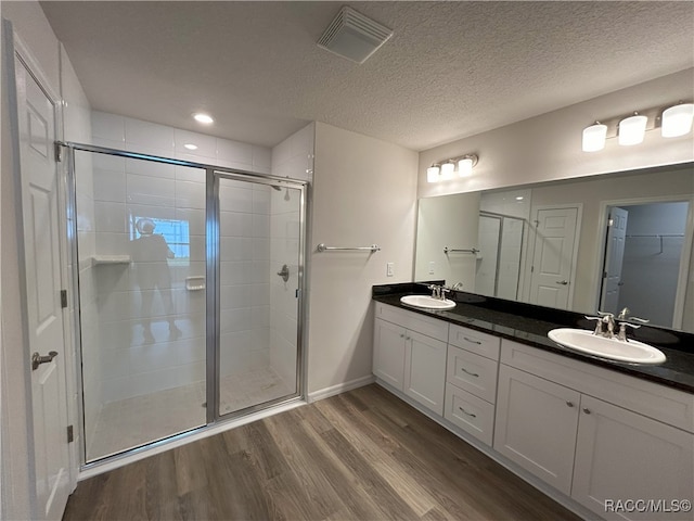 bathroom with an enclosed shower, vanity, wood-type flooring, and a textured ceiling