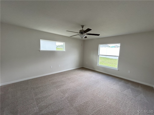 carpeted spare room featuring ceiling fan and a healthy amount of sunlight