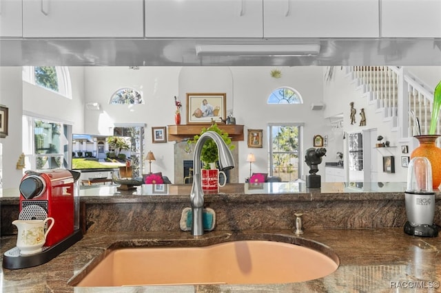 kitchen with dark stone counters, white cabinetry, a healthy amount of sunlight, and sink