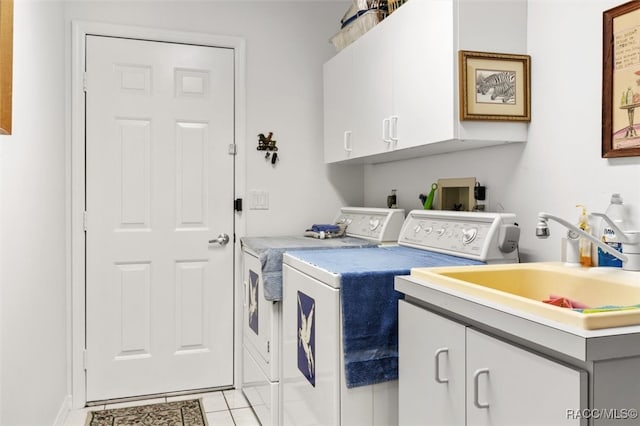 clothes washing area with washing machine and clothes dryer, sink, light tile patterned flooring, and cabinets