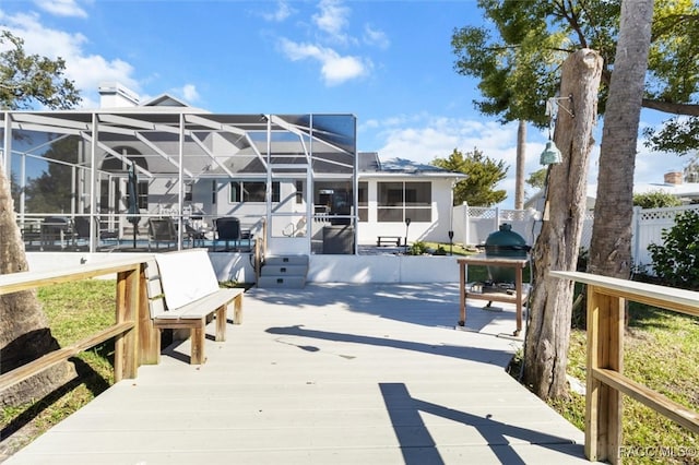 wooden deck featuring glass enclosure and area for grilling