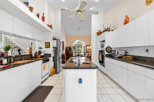 kitchen with white cabinetry, a center island, sink, a towering ceiling, and black appliances