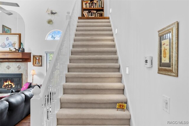 stairs featuring a towering ceiling, hardwood / wood-style flooring, and a tiled fireplace